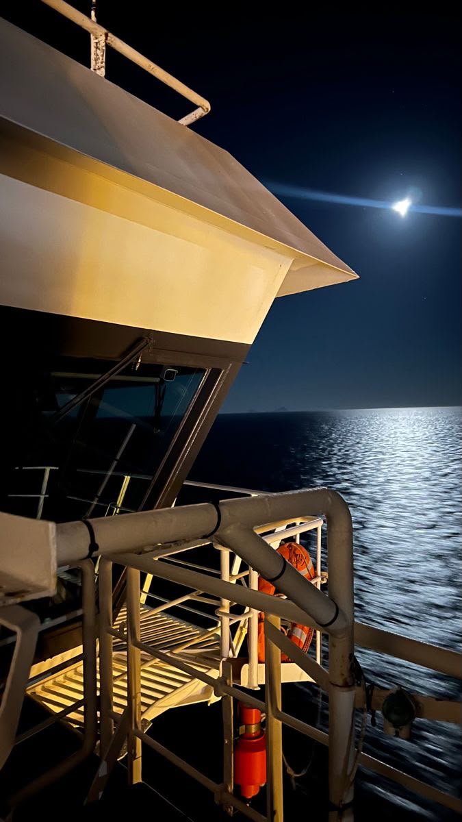 Vessel deck at night under moonlight on open water