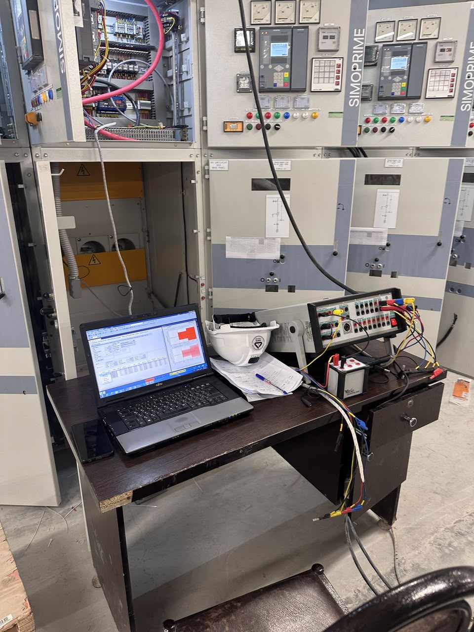 Industrial switchgear panel undergoing testing and commissioning with a laptop